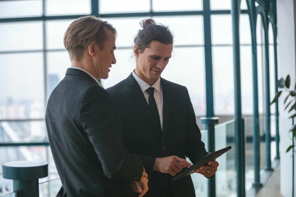 Zwei Männer in Anzügen schauen sich ein Tablet an
